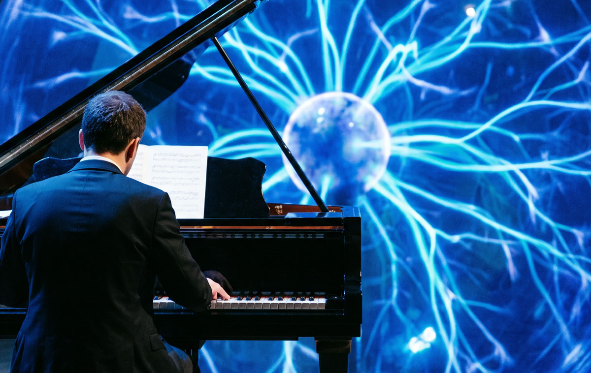 Pianista di spalle davanti a una grande sfera al plasma